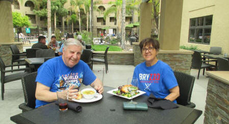 Image may contain: 2 people, including Greg Lopatka, people smiling, people sitting, table, food, outdoor and indoor